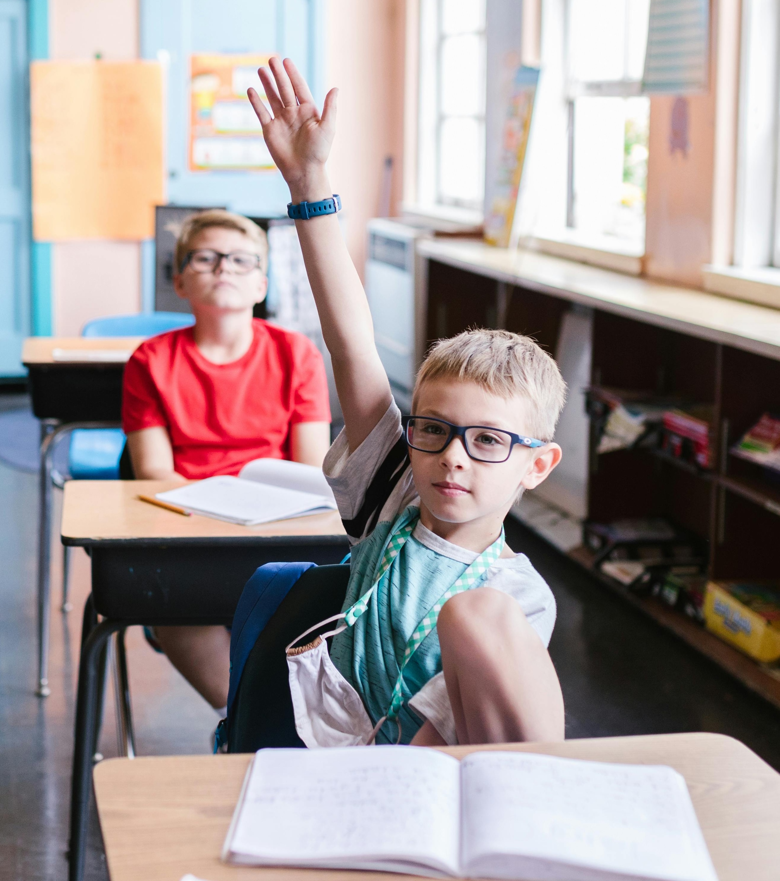 Child sitting in class room and raising hand